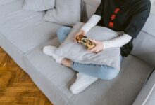 Person sitting on a couch playing video games, symbolizing leisure and entertainment.