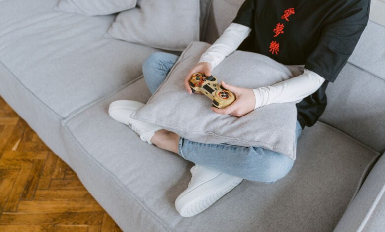 Person sitting on a couch playing video games, symbolizing leisure and entertainment.