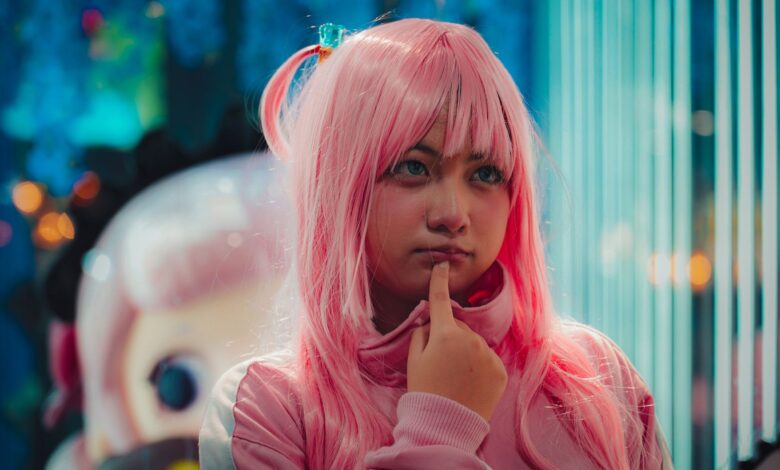 Close-up of young woman in pink wig and costume, pondering indoors.