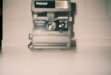 Blurred vintage Polaroid camera on a white surface creating a nostalgic feel.