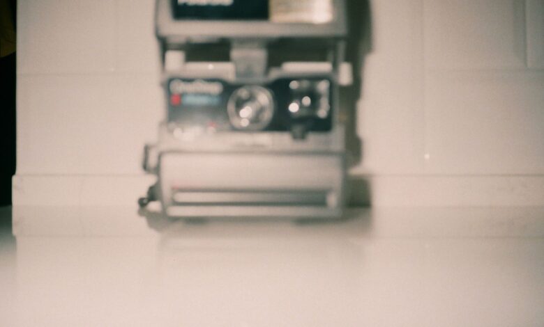 Blurred vintage Polaroid camera on a white surface creating a nostalgic feel.