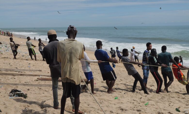 Men on the beach engaged in a tug of war, displaying teamwork and strength.