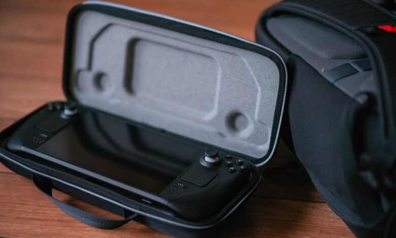 A close-up of a portable gaming device in a protective case next to a bag on a wooden floor.