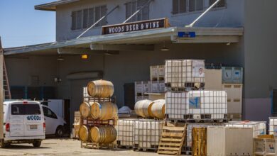 Outdoor view of a brewery with stacked barrels and a delivery van showcasing industrial beer production.