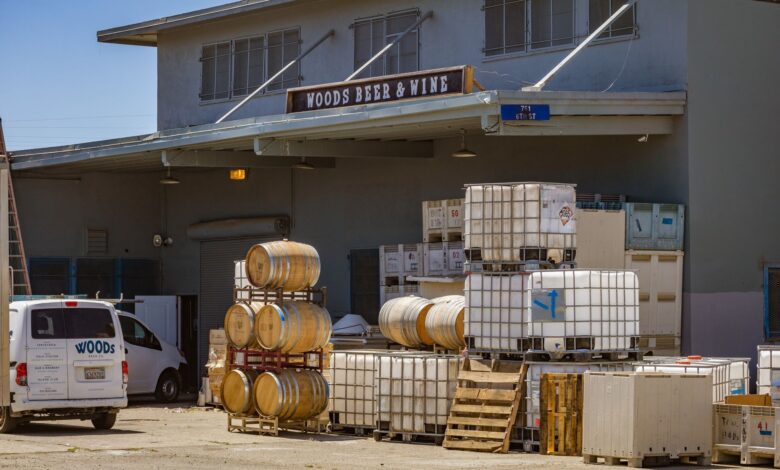 Outdoor view of a brewery with stacked barrels and a delivery van showcasing industrial beer production.