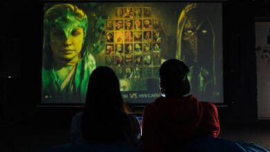 Two people sitting indoors gaming on a large projector screen, enjoying a video game session.