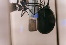 Close-up of a condenser microphone with pop filter in a studio setting, ideal for audio and podcasting.
