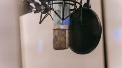 Close-up of a condenser microphone with pop filter in a studio setting, ideal for audio and podcasting.