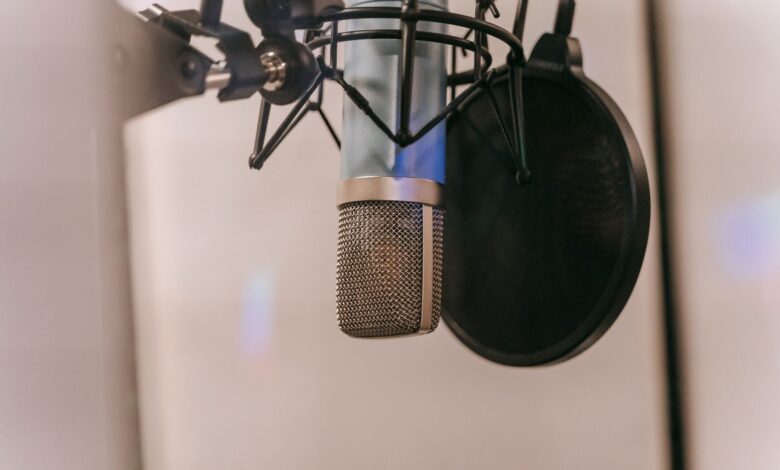 Close-up of a condenser microphone with pop filter in a studio setting, ideal for audio and podcasting.