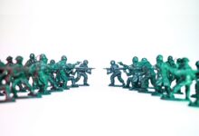 Green toy soldiers facing off on a white background, symbolic of conflict and strategy.