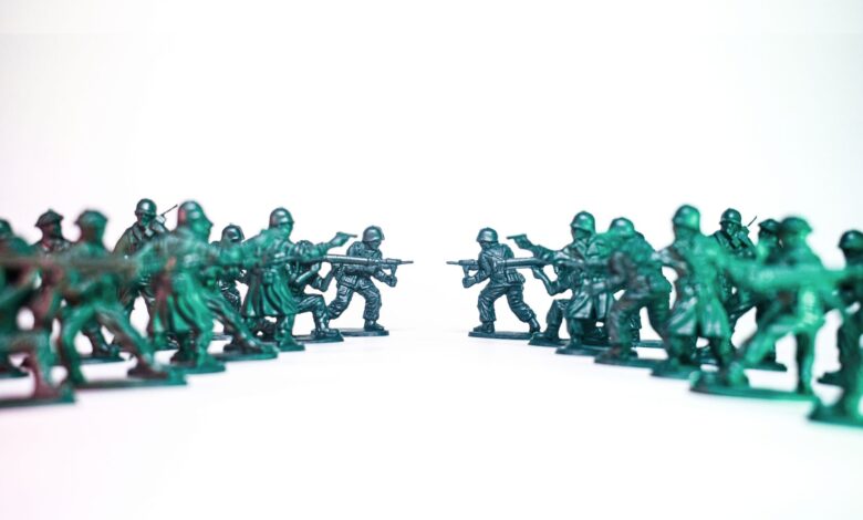 Green toy soldiers facing off on a white background, symbolic of conflict and strategy.