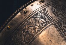 Close-up of an intricately designed antique metal shield with detailed engravings and brass rivets.
