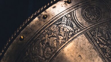 Close-up of an intricately designed antique metal shield with detailed engravings and brass rivets.