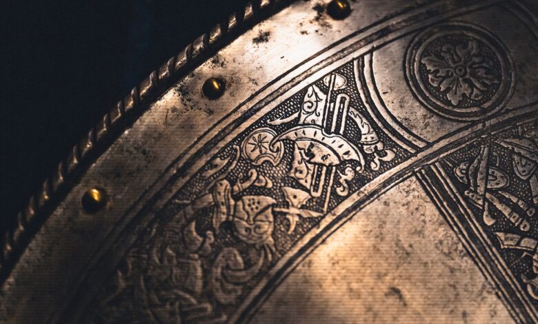 Close-up of an intricately designed antique metal shield with detailed engravings and brass rivets.