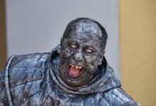 A person wearing a detailed stone statue costume with a scary expression in Kroměříž.