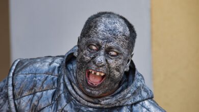 A person wearing a detailed stone statue costume with a scary expression in Kroměříž.