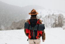 Back view of a male hiker in winter gear walking through a snowy landscape.