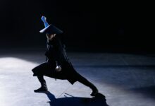 A skilled cosplayer strikes a dramatic pose as a game character in a dark studio setting.