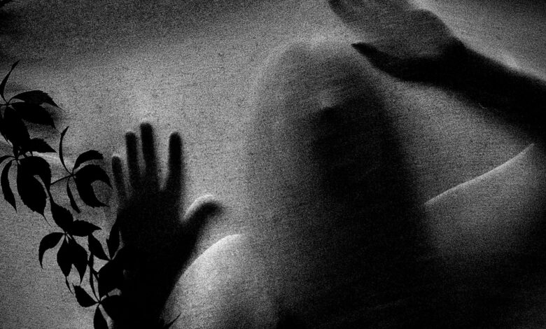 Mysterious figure with hands pressed against frosted glass, evoking a spooky atmosphere.