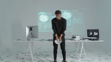 A man stands holding money in a high-tech room with scattered bills and a computer setup.