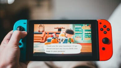 Crop anonymous person playing videogame while using game console and sitting at home on blurred background