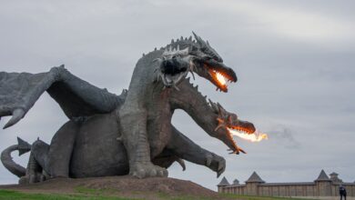 Majestic dragon sculpture breathing fire, set in an open park area, perfect attraction for fantasy lovers.