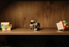 A collection of various Rubik's cubes displayed on a wooden shelf, showcasing unique designs and patterns.