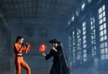 Two cosplayers in dynamic fighting pose inside industrial building.