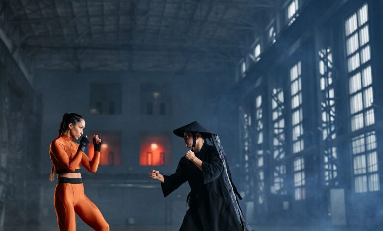 Two cosplayers in dynamic fighting pose inside industrial building.
