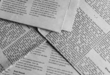 Black and white close-up of newspaper pages with text in Dutch.