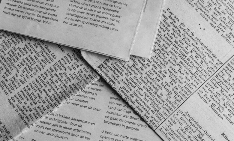 Black and white close-up of newspaper pages with text in Dutch.