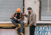 Two men interacting with a synthesizer against an urban backdrop.