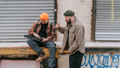 Two men interacting with a synthesizer against an urban backdrop.