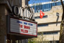 Cinema marquee displaying movie title in urban setting with Swiss flag nearby.