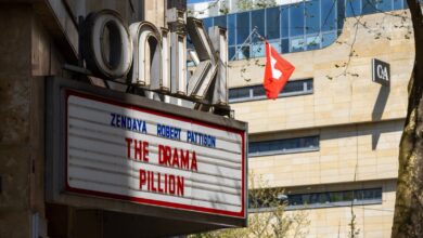 Cinema marquee displaying movie title in urban setting with Swiss flag nearby.
