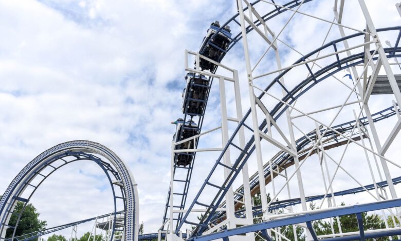 Experience the adrenaline rush of a steel roller coaster under blue skies at an amusement park.