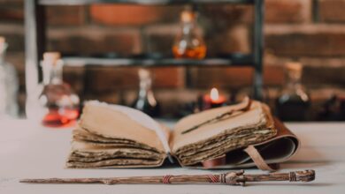 Close-up of a wooden wand and ancient spell book in a mystical, rustic environment.