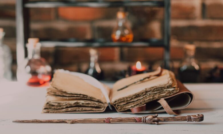 Close-up of a wooden wand and ancient spell book in a mystical, rustic environment.