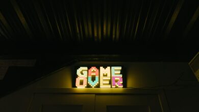 Glowing neon sign with pixelated Game Over text in a dark arcade setting.