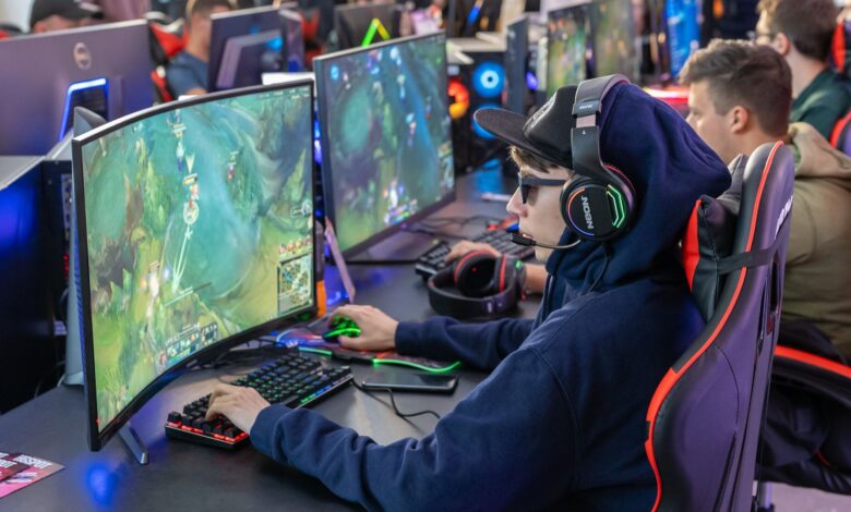 Gamers in an esports tournament playing on high-end gaming setups with monitors, keyboards, and headphones.