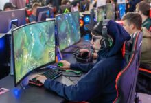 Gamers in an esports tournament playing on high-end gaming setups with monitors, keyboards, and headphones.