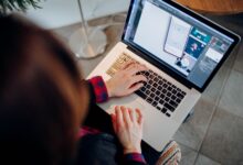 Close-up of a person working on a laptop with graphic design software.