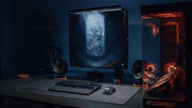 A stylish gaming setup featuring a screen, keyboard, and PC with ambient lighting.