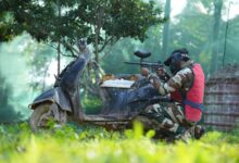Person in camouflage gear playing paintball outdoors in Bengaluru, Karnataka.