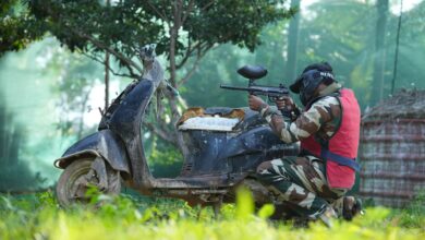 Person in camouflage gear playing paintball outdoors in Bengaluru, Karnataka.