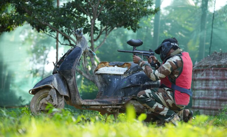 Person in camouflage gear playing paintball outdoors in Bengaluru, Karnataka.
