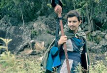Man wearing medieval cosplay costume holding staff in a forest setting in Colombia.
