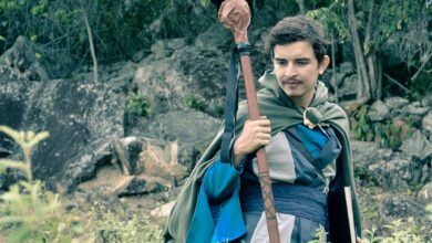 Man wearing medieval cosplay costume holding staff in a forest setting in Colombia.