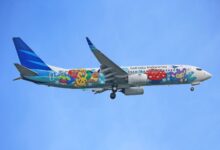 Garuda Indonesia airplane featuring Pokémon artwork flying against a clear blue sky.