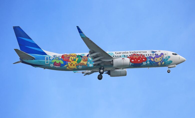 Garuda Indonesia airplane featuring Pokémon artwork flying against a clear blue sky.